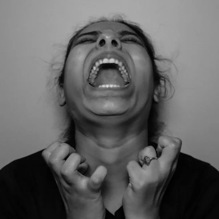 a woman with her mouth open and hands in front of her face